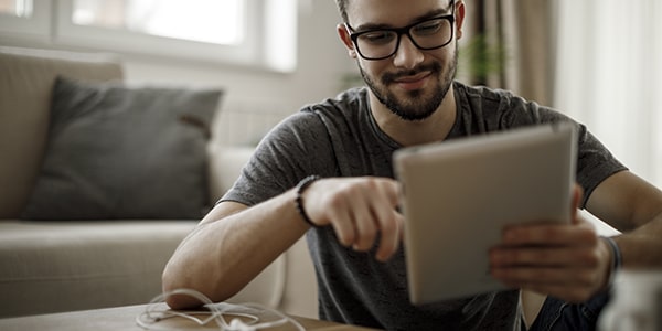 Hombre joven leyendo desde una biblioteca virtual en una tableta Hombre joven leyendo desde una biblioteca virtual en una tableta