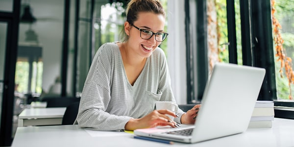 Mujer joven utilizando herramientas digitales con una computadora al frente