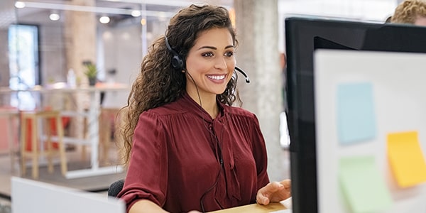 Mujer joven trabajando con una computadora, con audiculares y micrófonos Mujer joven trabajando con una computadora, con audiculares y micrófonos
