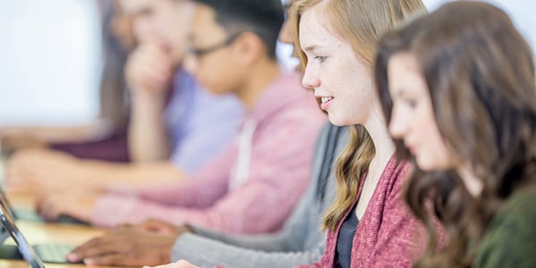 Grupo de adolescentes realizando pruebas de inglés a través de una computadora