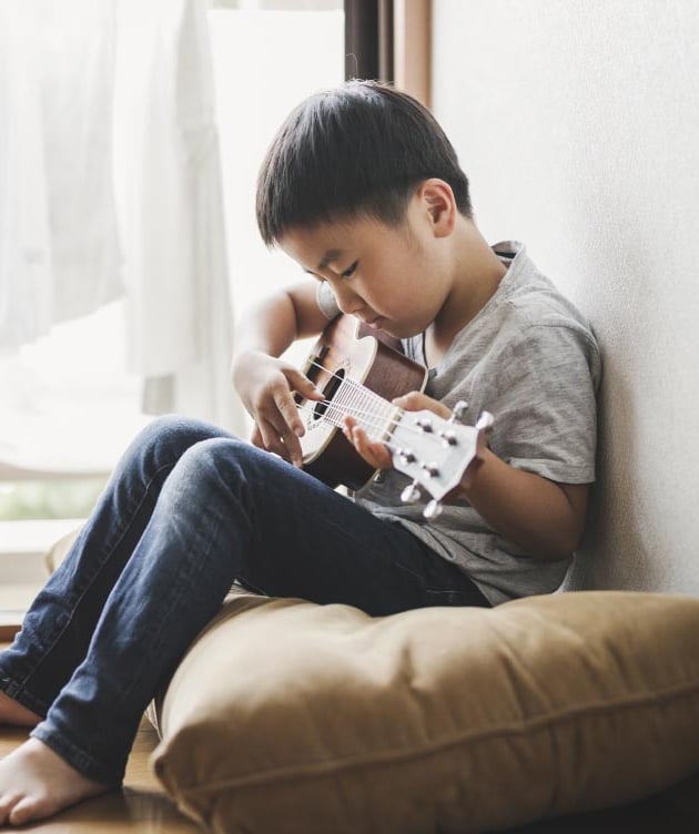 Niño tocando la guitarra sentado