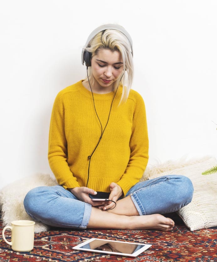 Mujer joven sentada en el piso leyendo desde un teléfono móvil